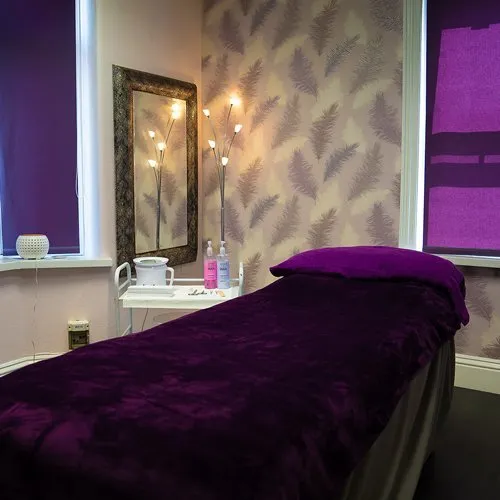 A treatment room with the massage bed covered in purple